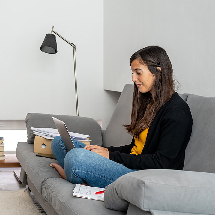 Smiling woman sitting on couch with laptop